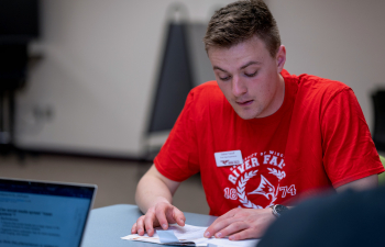 A male student reviews documents on a table in front of him