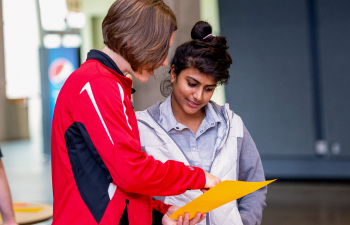 A professor points to a sheet of paper for a student