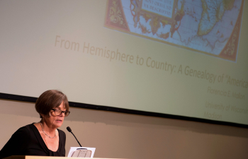 A professor speaks to a crowd from behind a podium