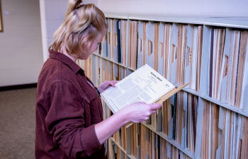 A female student flips through a book in the library