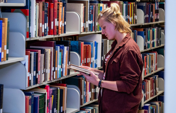 A student browsing stacks of books in the library