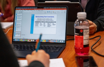 Looking over a student's shoulder at a powerpoint on their laptop in a study room
