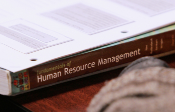 A textbook about Human Resource Management sits on a desk