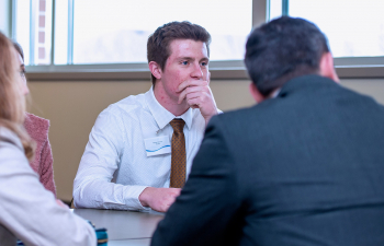 A male student listens to another person as they sit at a table during the Innovation Challenge