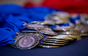 A stack of medals with blue ribbons sit on a table