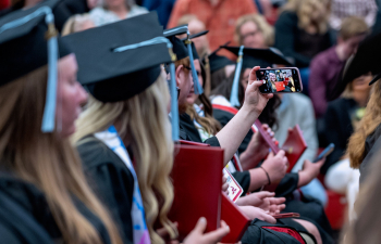 Graduates take a selfie while they attend commencement