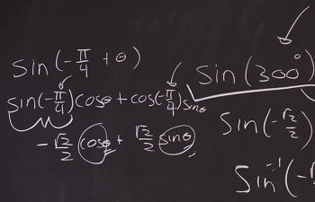 A math problem is written on a blackboard with white chalk