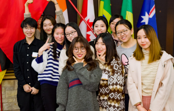 A group of international students pose in front of country flags