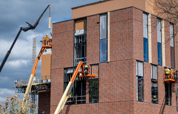 Construction workers work on the exterior of SciTech