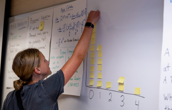 A female student puts a post it note on a whiteboard