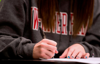 A female student uses a pen to write in a spiral notebook