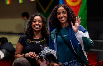 Two women smile and wave at the camera during a DIB event