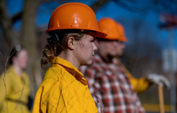 A group of people wear orange hard hats