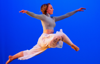 A female student leaps through the air during a dance performance