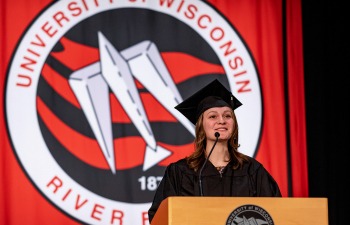 A female speaker stands at a podium during commencement.