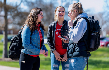 Three female students talk outside on the campus mall