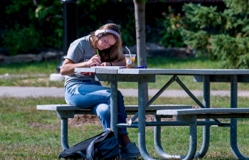 Student does homework at a picnic table on a spring day
