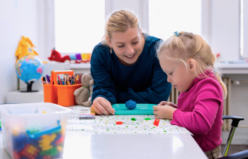 A school psychology graduate student speaks to a young child in a classroom