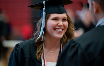 A female student attends graduation wearing a cap and gown