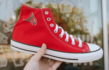 A student holds up a pair of exclusive Falcon Converse.