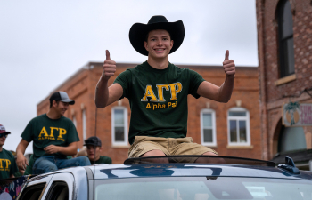A fraternity member sits on a vehicle during the Homecoming parade