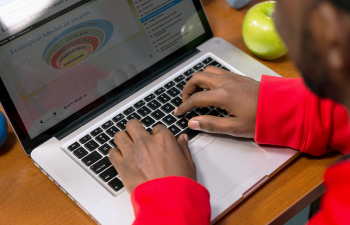 A Health and Wellness management student creates a powerpoint presentation on their laptop