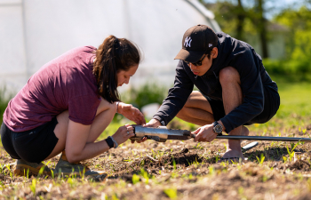 Two students drill the dirt and collect dirt cores to study