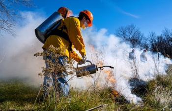 Agriculture student sprays a planned prairie fire near campus