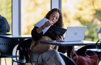 A female student sits at a table reviewing paperwork for a class