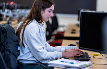 A female student types on a keyboard in a engineering classroom
