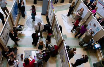 A group of people stand in the Madison State Capital building rotunda and present their research posters
