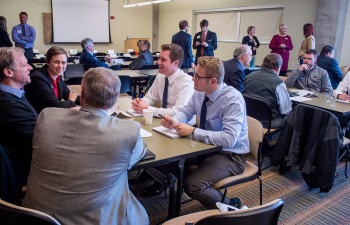 A group of people are in a conference room mingling