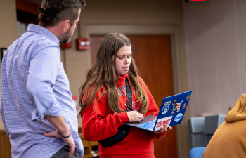 A student speaks to a professor holding their laptop