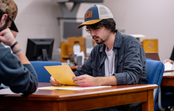 A male student reviews a piece of paper during class
