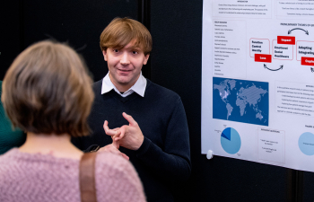 A male student presents their research poster to the community