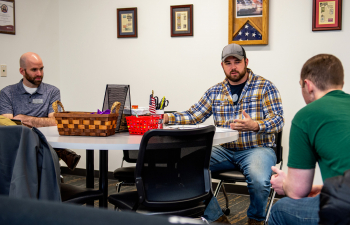 Three male students sit talking in the Military and Veteran lounge