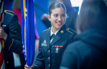 A female military service member holds the Wisconsin state flag