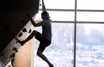 Student ascends the rock climbing wall in the Falcon Center