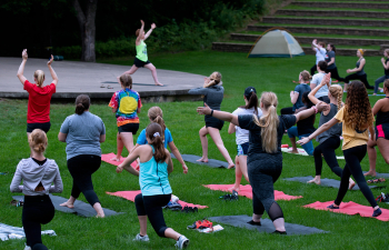A group of women practice yoga at the Melvin Wall Amphitheatre
