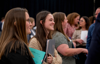 A student smiles while speaking with an employer at the Career Fair