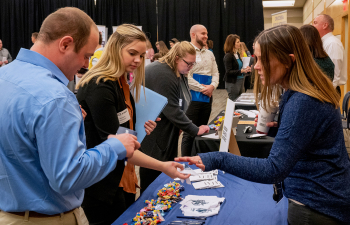 Two students speak with an employer at a booth at the career and internship fair