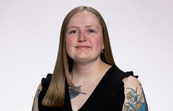 Headshot of Codie Ishcomer, a young woman with long blonde hair and colorful tattoos wearing a black tank top