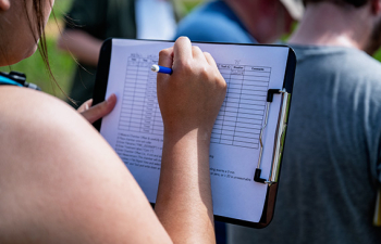 A Community and Environmental Planning student is writing on a clipboard