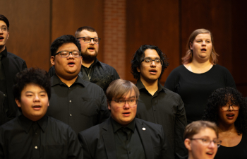 People dressed in black clothing sing with a choir