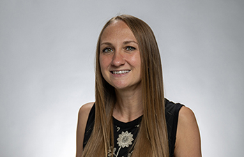 Corinne Franz headshot, woman with long light brown hair wearing a black sleeveless top