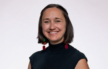 Headshot of Elise Peters, a young woman with short black hair and red earrings wearing a black tank top blouse