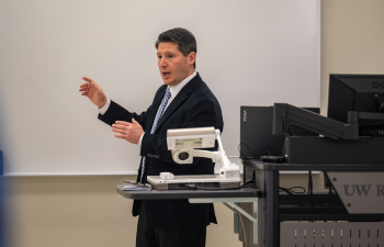 male faculty member stands at whiteboard while talking to a class