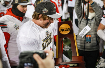a UWRF football player holds the national championship trophy on the field after the game