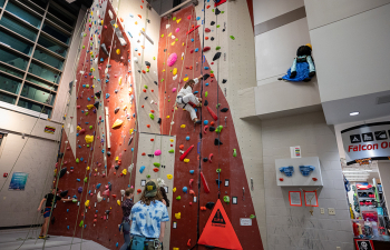 People climb the Falcon Center rock wall