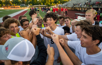 the men's soccer team celebrates in a huddle